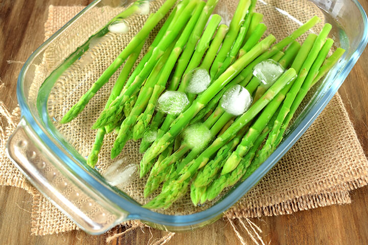 Asperges blanchies dans un plat d’eau froide avec glaçons pour les conserver au congélateur