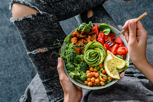 Femme qui mange un bol végane avec légumes