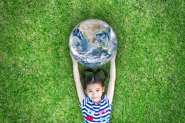 Fillette étendue dans l'herbe et tenant une planète terre entre ses mains