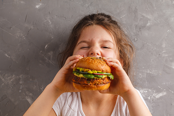 Fillette qui mange un burger de protéines végétales