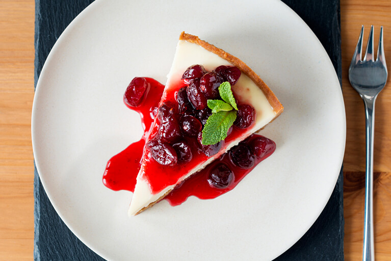 Une part de gâteau au fromage végétalien garnie de cerises, vue de dessus, prête à être dégustée!