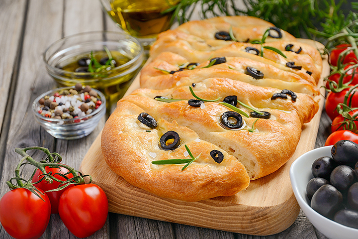 Pain focaccia italien avec olives, romarin, huile d’olive, tomates, sel et poivre
