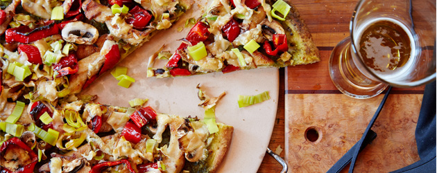 Pizza au poulet, poireaux, poivron rouge, champignons avec pesto et fromage sur un pain Naan