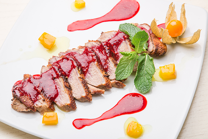 Poitrine de canard avec sauce aux framboises, poivron jaune et cerise de terre en décoration