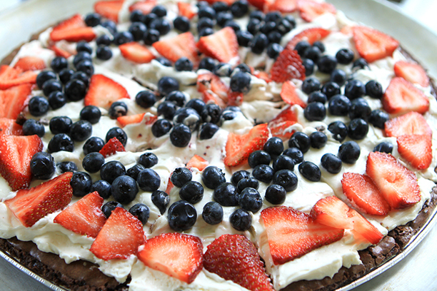 Recette de pizza dessert sucrée avec brownies comme croûte et garniture aux fraises, aux bleuets et au fromage à la crème