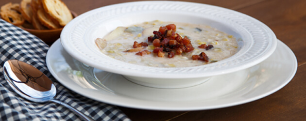 Un bol de soupe crémeuse avec des lardons déposés sur le dessus.