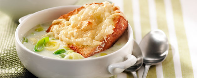 Bol de soupe gratinée aux poireaux avec une tranche de pain gratinée déposée dans le bol.