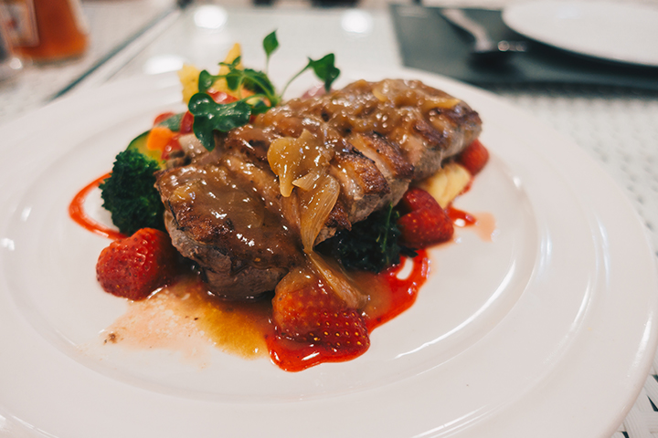 Suprêmes de canard barbecue nappées d’une sauce aux fraises dans une assiette blanche