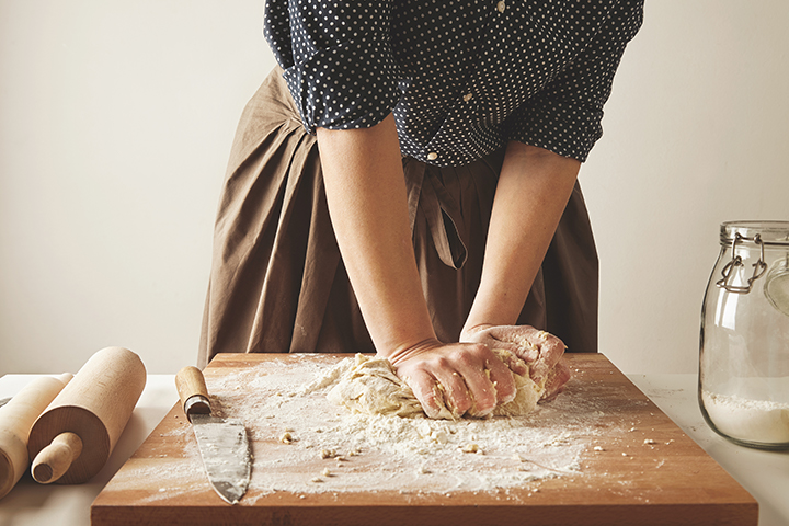 Une personne pétrit la pâte et ajoute de la farine pour éviter qu’elle colle