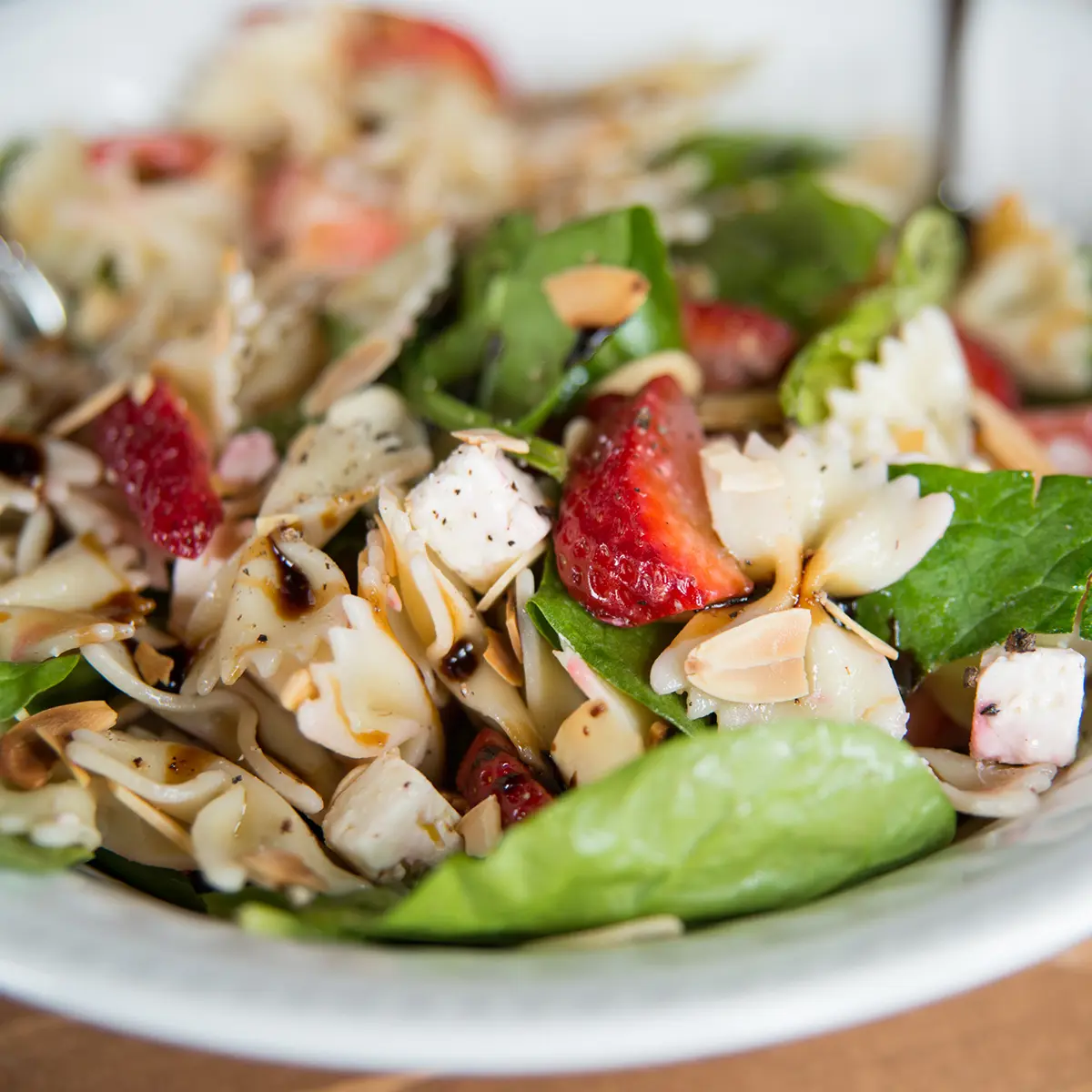Pasta salad with leeks, spinach, strawberries, sliced almonds and feta cheese
